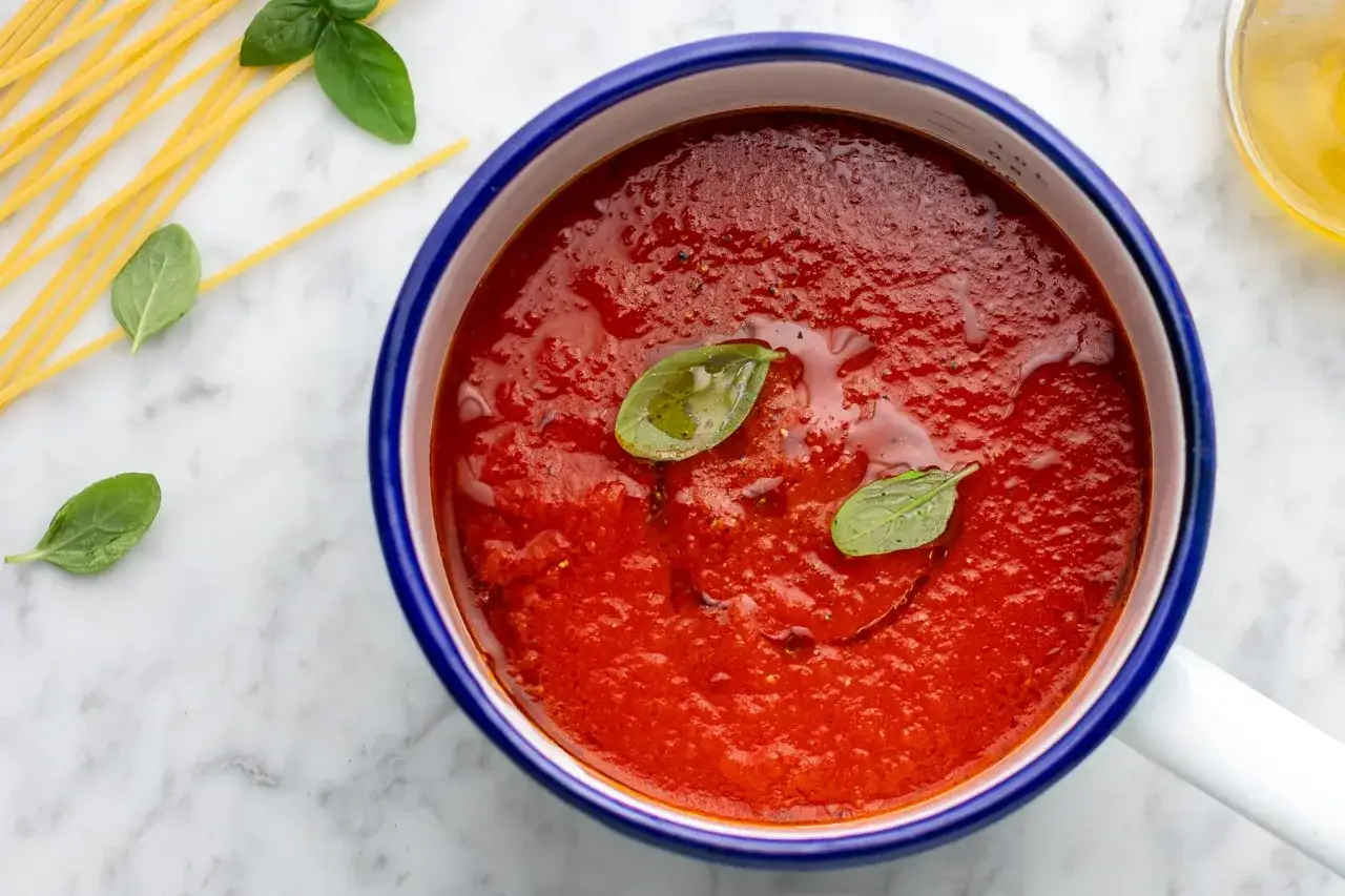 Sugo con pomodorini freschi, profumato al basilico, pronto per condire spaghetti dorati.