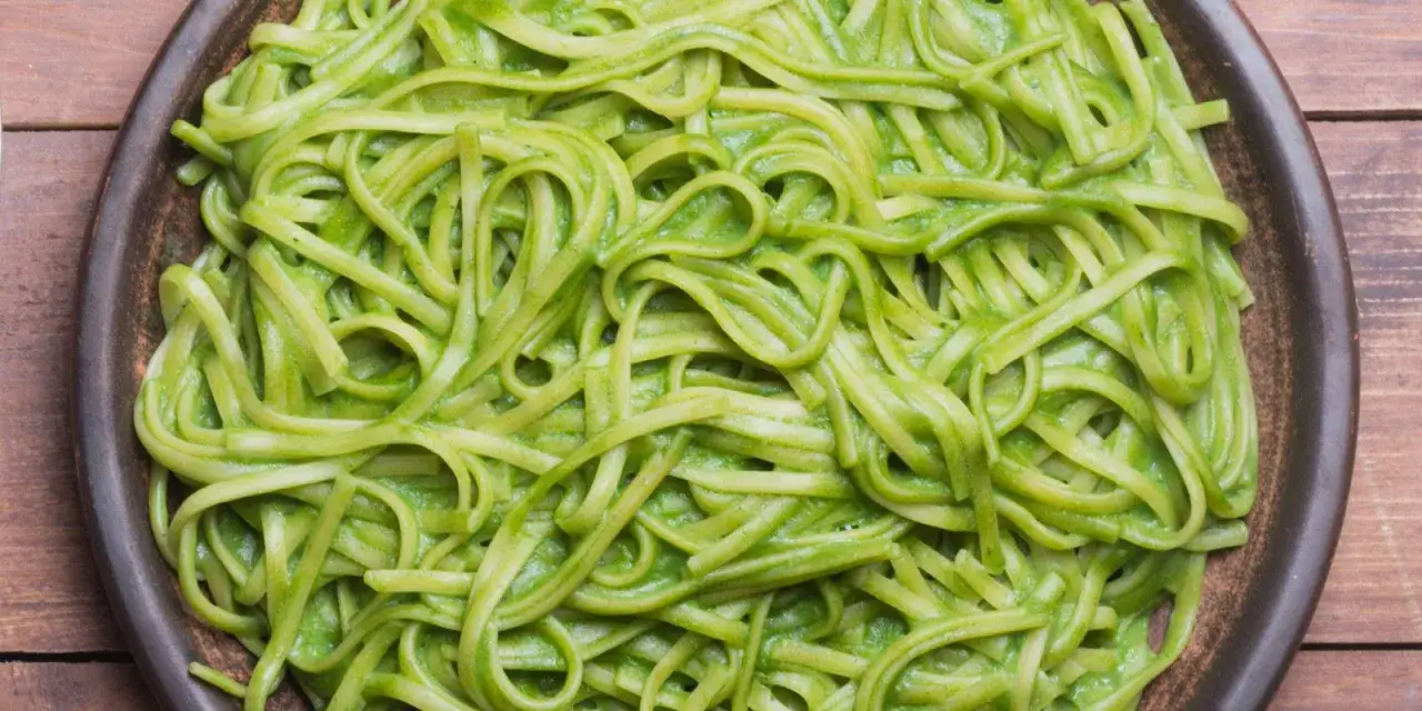 Pasta linguine condita con una cremosa salsa verde, probabilmente crema di zucchine per pasta, servita in un piatto scuro.