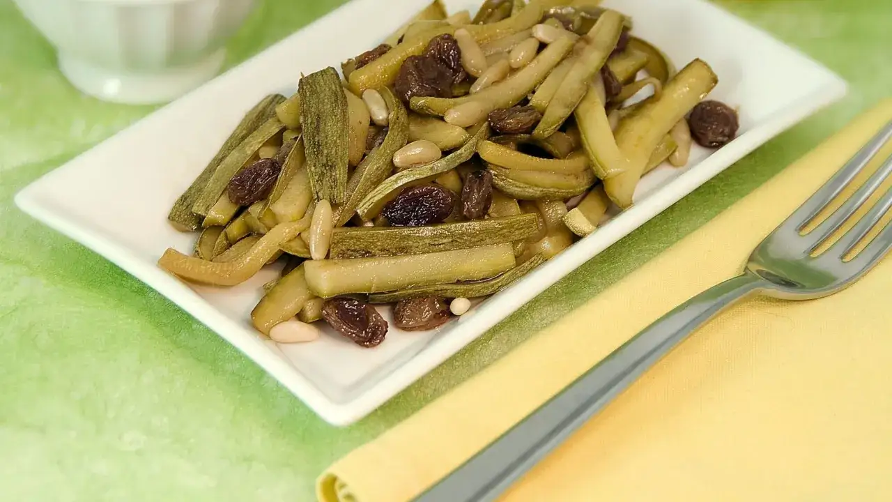 Zucchine in agrodolce con uvetta e pinoli, un piatto saporito e colorato.
