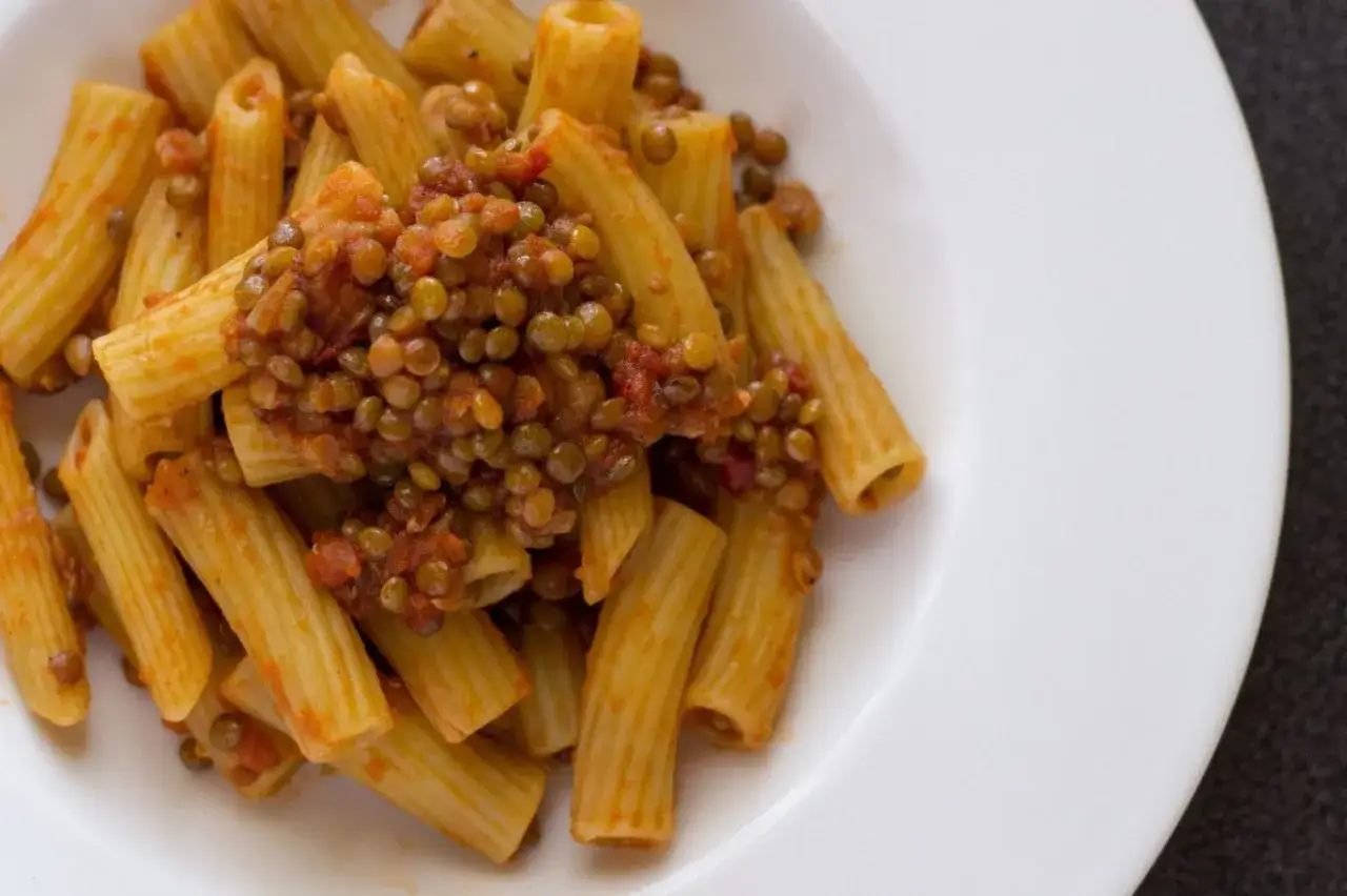 Piatto di rigatoni conditi con un saporito rag&ugrave; di lenticchie, un classico della cucina italiana.