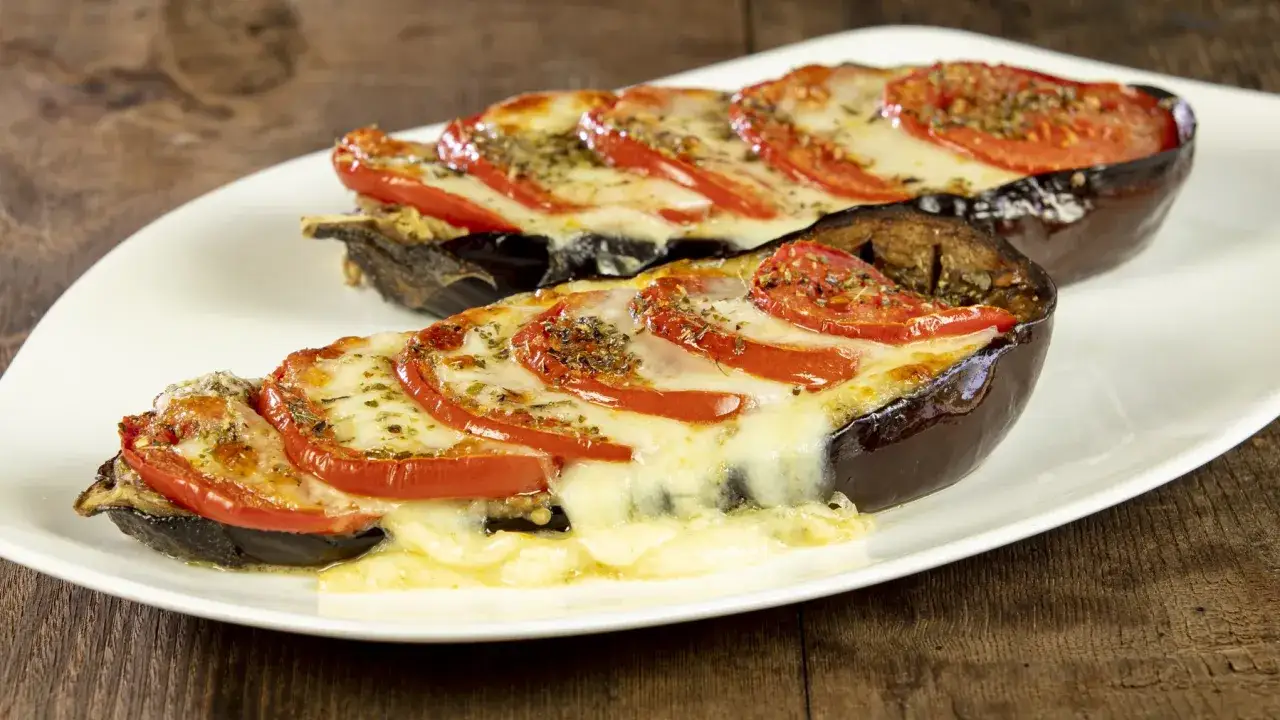 Melanzane ripiene al forno velocissime, con pomodoro e formaggio filante, pronte per essere gustate.