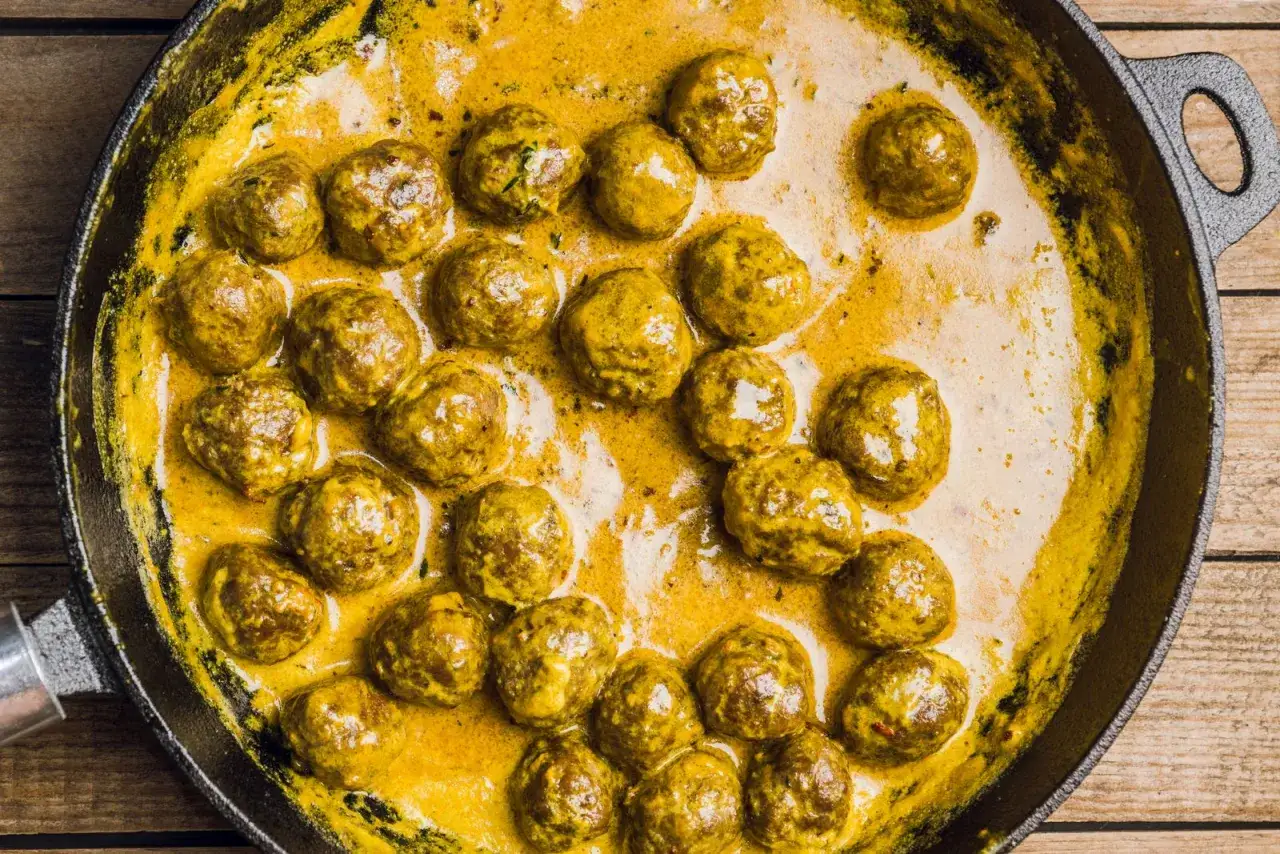 Polpette in bianco cremose in padella, dorate e succulente, immerse in una salsa gialla e invitante.