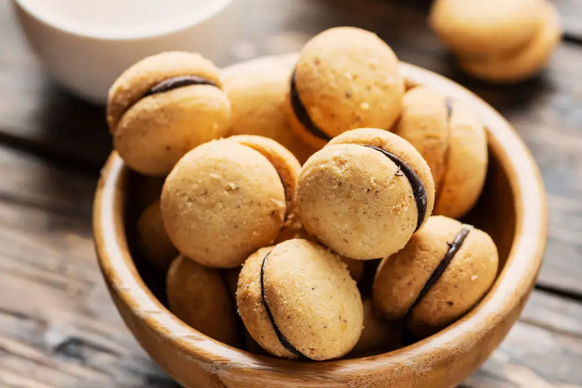 Baci di dama, deliziosi biscotti alle nocciole con ripieno di cioccolato, in una ciotola di legno.