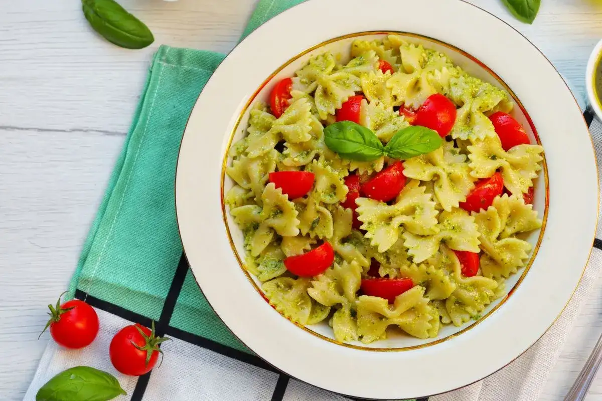 Farfalle condite con pesto e pomodorini freschi, un piatto di pasta alla crudaiola che profuma d'estate.