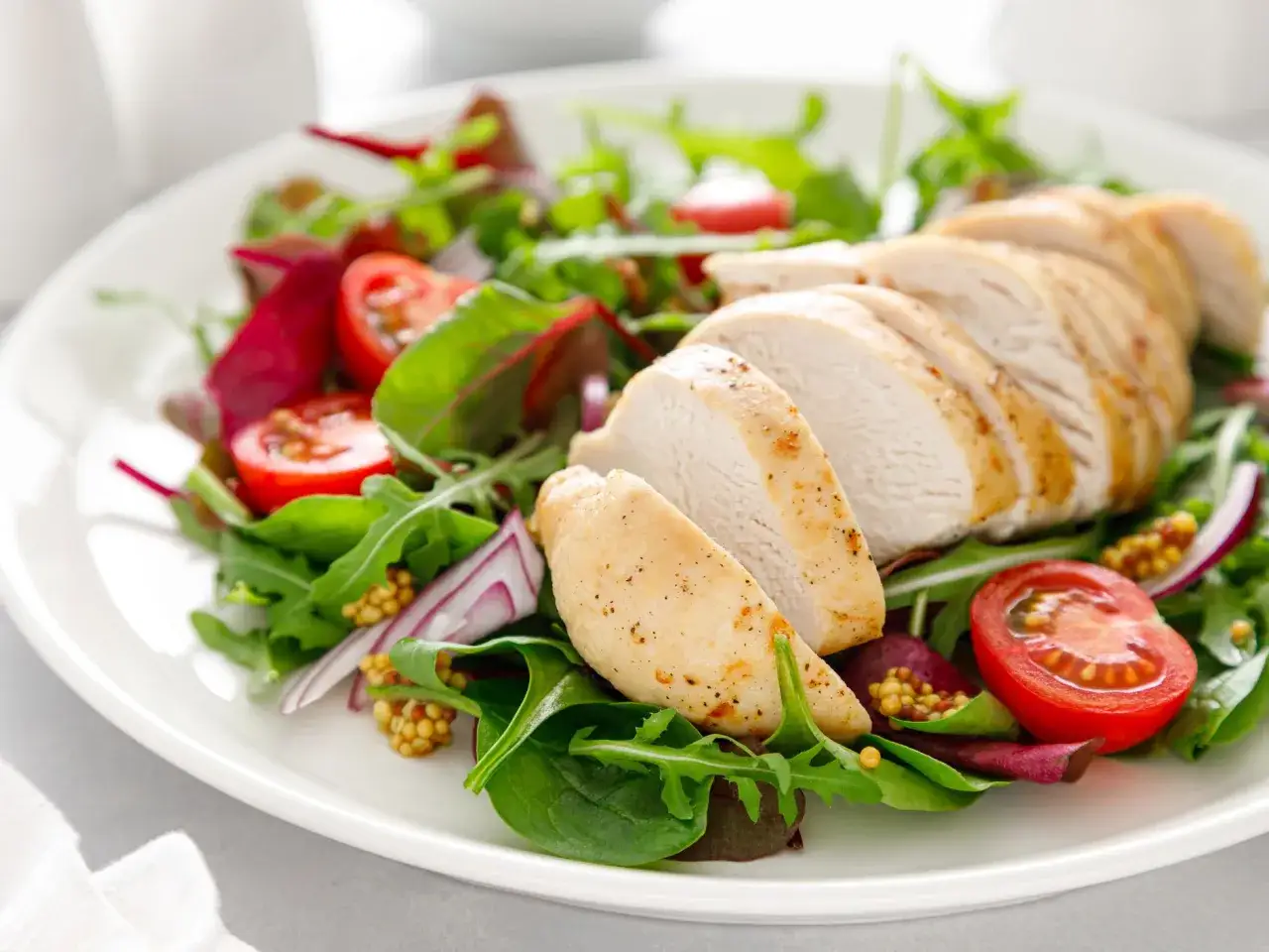 Deliziosa tagliata di pollo su un letto di insalata mista, pomodorini e cipolla rossa.