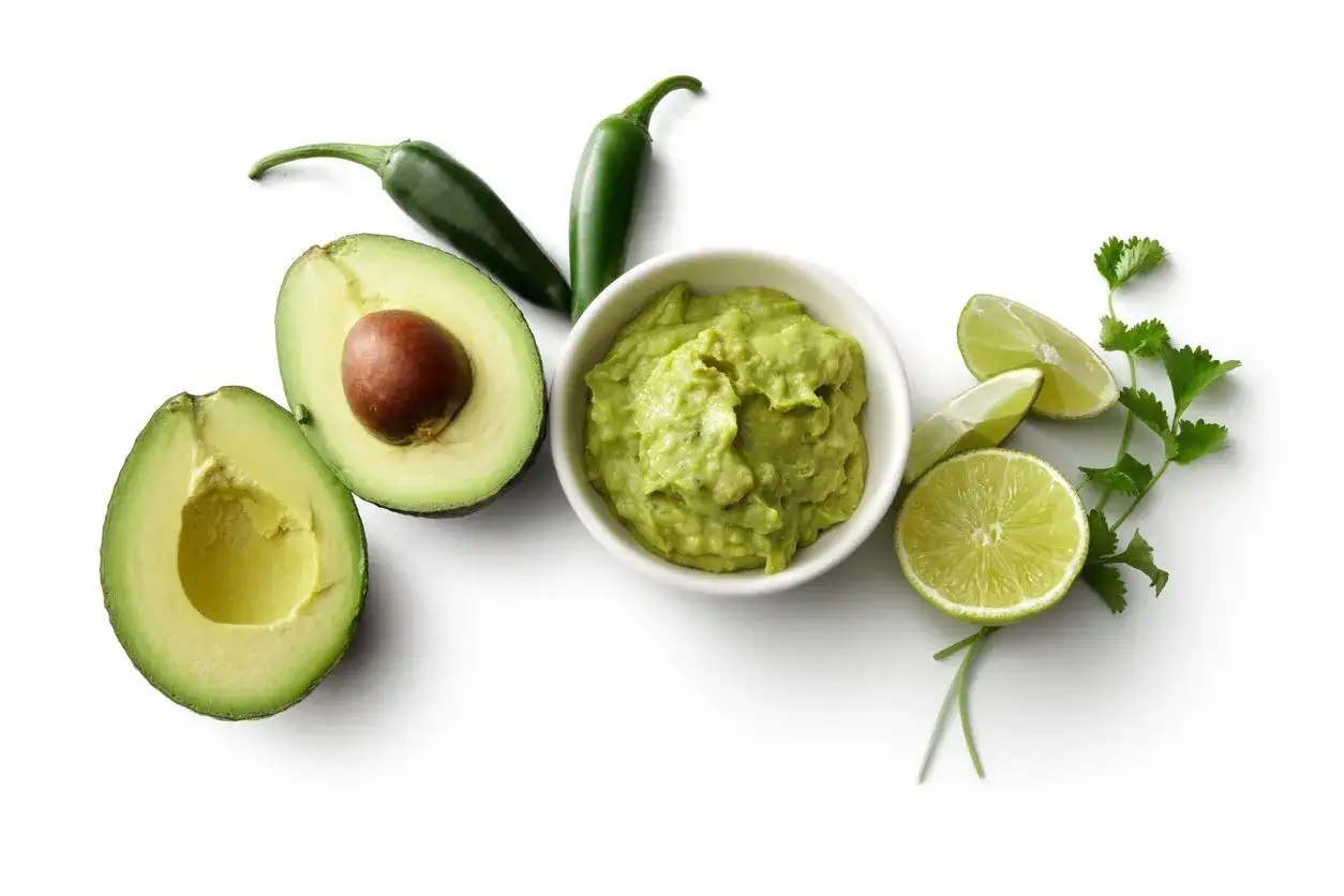 Ingredienti per la salsa guacamole ricetta: avocado, peperoncini jalape&ntilde;o, lime e coriandolo su sfondo bianco.