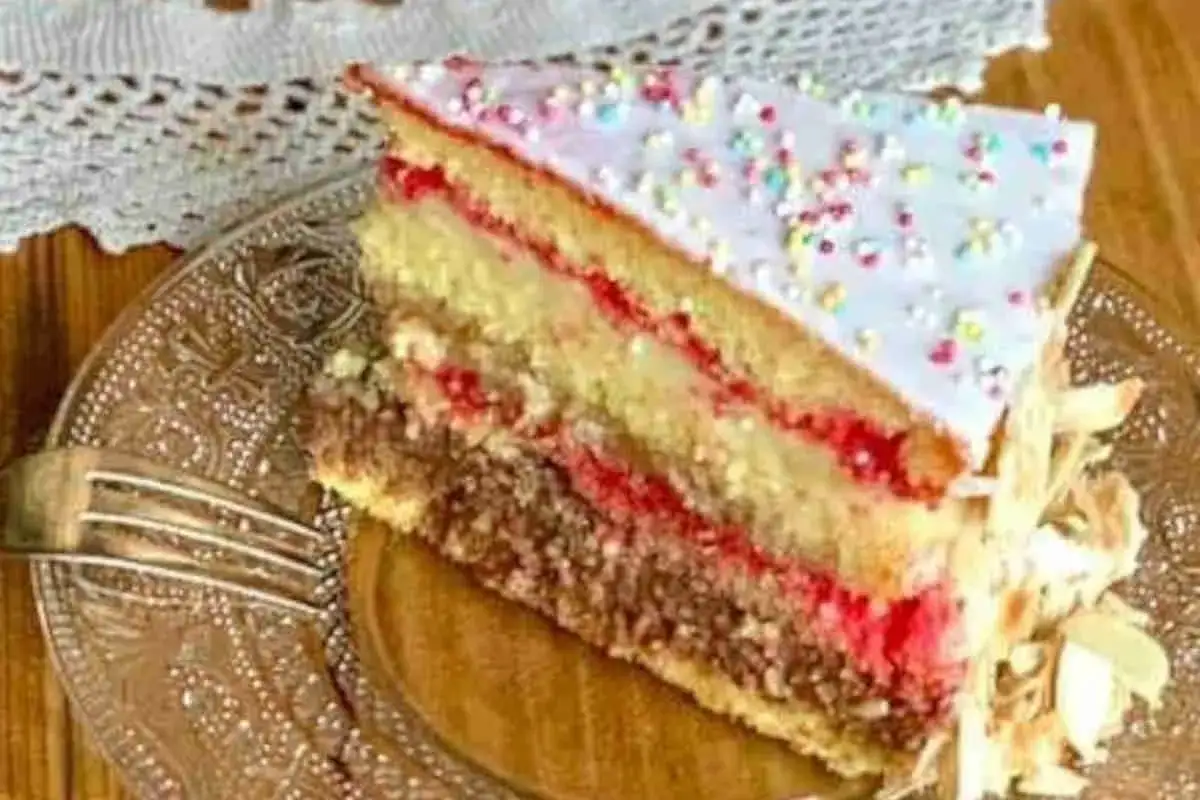 Fetta di pizza dolce abruzzese con strati di pan di Spagna, crema e confettura, guarnita con glassa e codette colorate.