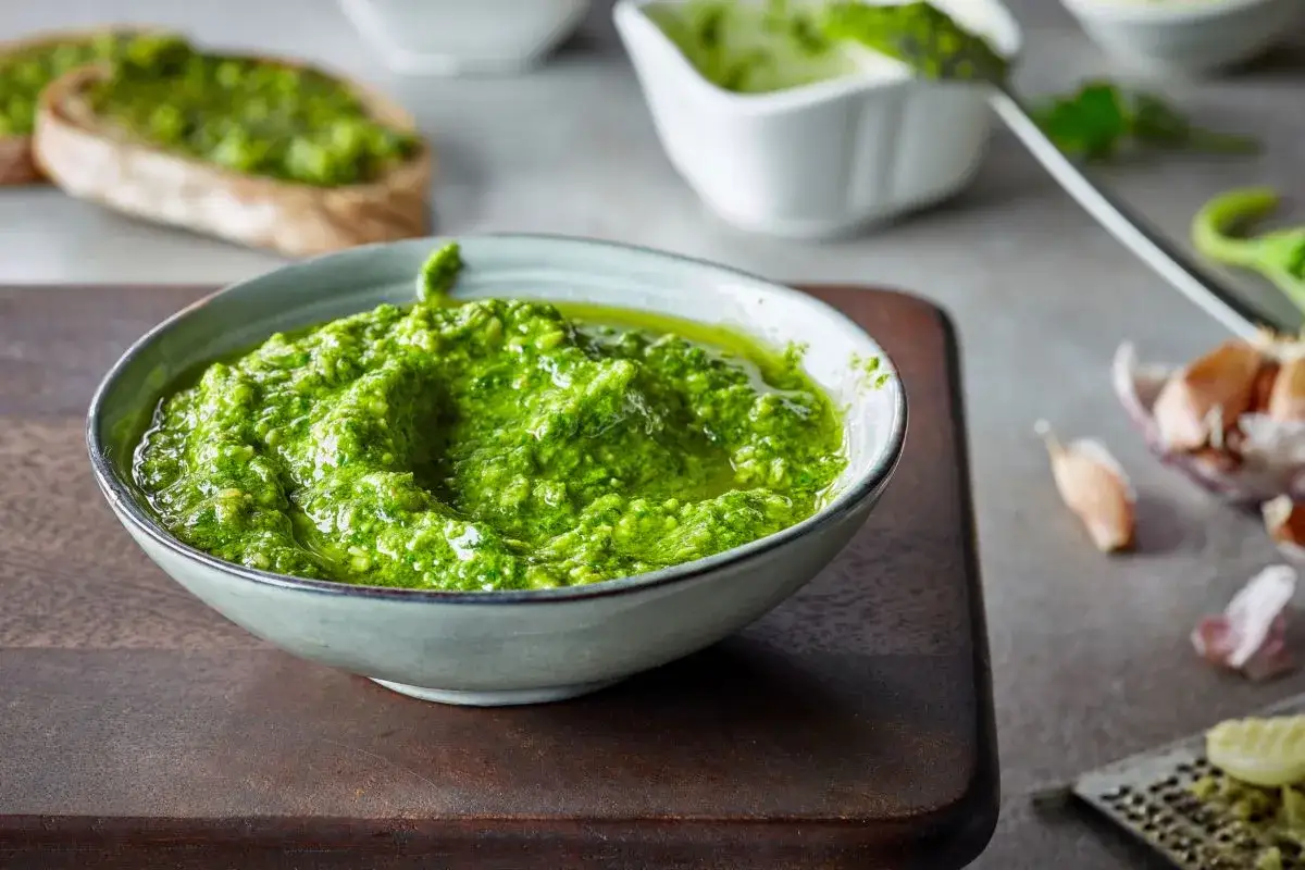 Una ciotola di pesto fatto in casa, vibrante e profumato, pronto per essere gustato su crostini o pasta.