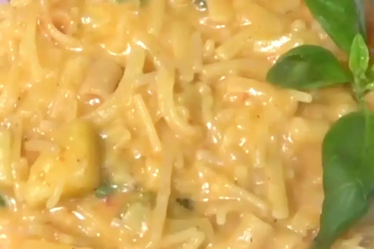 Un cremoso piatto di pasta e patate con provola filante, guarnito con foglie di basilico fresco.