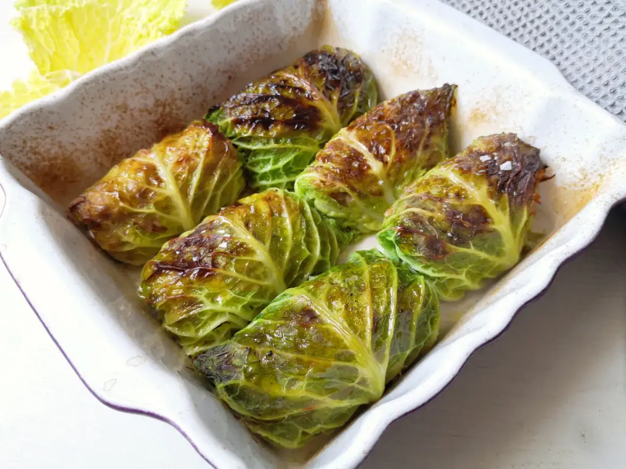 Involtini di verza dorati e succulenti, cotti in teglia, pronti per essere gustati.