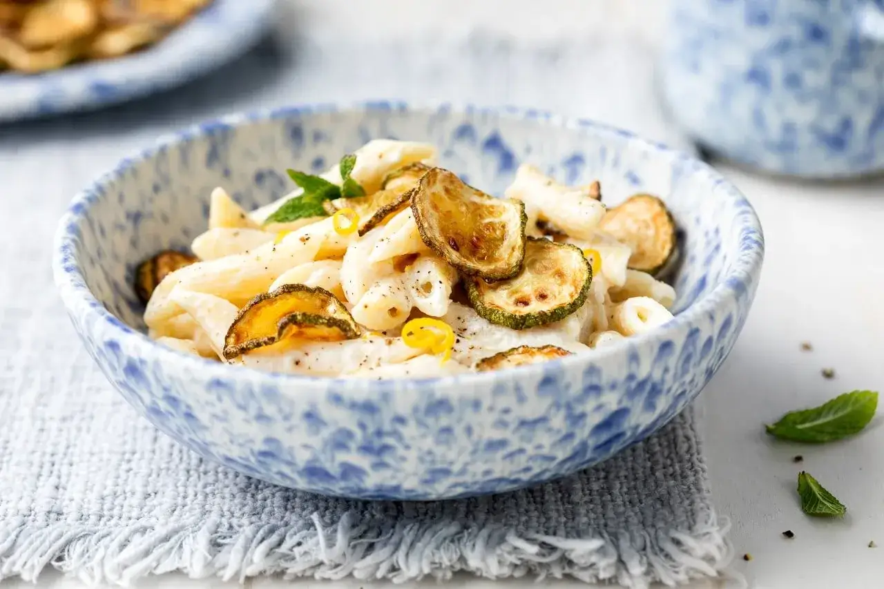 Penne con crema di zucchine, guarnite con zucchine fritte croccanti e scorza di limone.