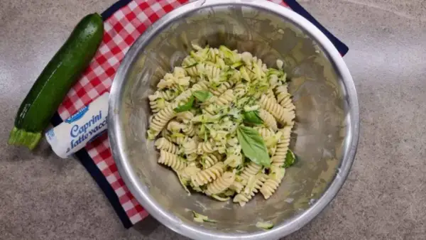 Pasta fredda con zucchine, basilico e formaggio fresco. Un piatto estivo leggero e gustoso, pronto per essere servito.