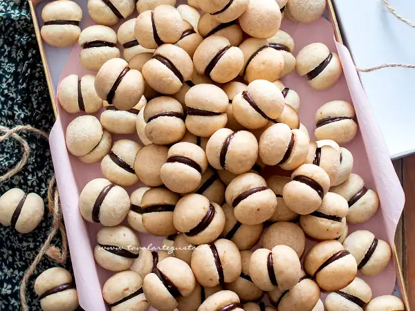 Una teglia piena di deliziosi baci di dama, biscotti friabili con un cuore di cioccolato fondente.