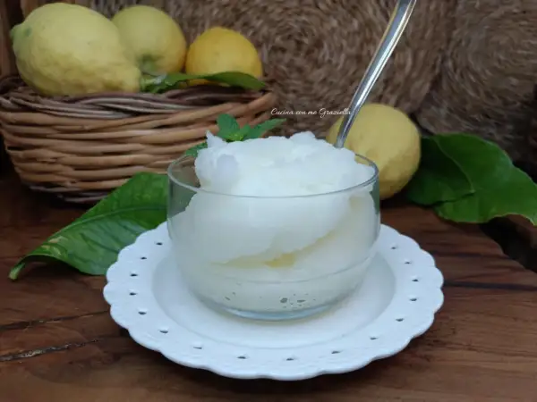 Una coppa di granita al limone, fresca e dissetante, con limoni freschi sullo sfondo.