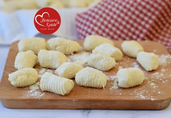 Gnocchi di ricotta freschi, pronti per essere cucinati, su un tagliere di legno.