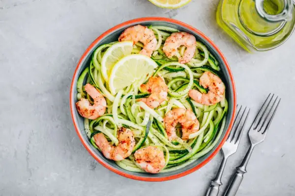 Spaghetti di zucchine con gamberi succulenti e spicchi di limone, un piatto leggero e gustoso.