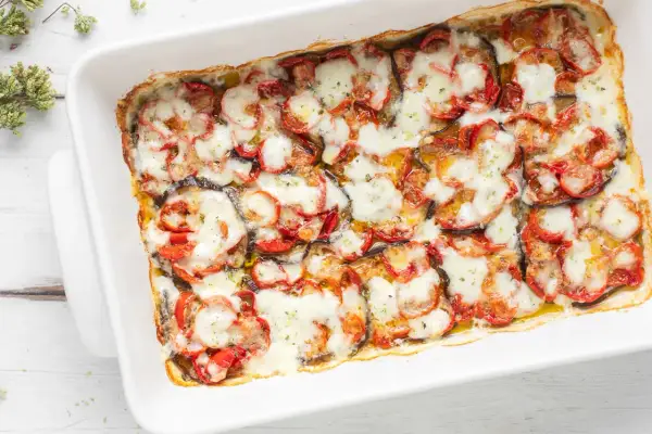 Melanzane al forno, un piatto invitante con fette di melanzane, pomodori e mozzarella filante, pronto per essere gustato.
