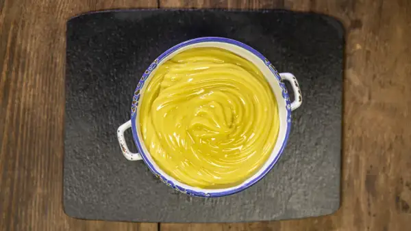 Una ciotola di cremosa crema pasticcera vegana, con un vortice lucido al centro, pronta per essere gustata.