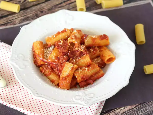 Piatto di rigatoni conditi con un sugo rosso piccante alla nduja, spolverati di parmigiano.