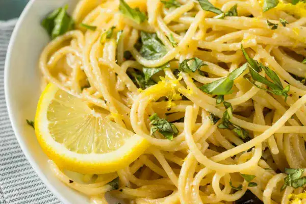 Spaghetti al limone freschi e profumati, guarniti con scorza di limone e basilico. Un piatto leggero e saporito.