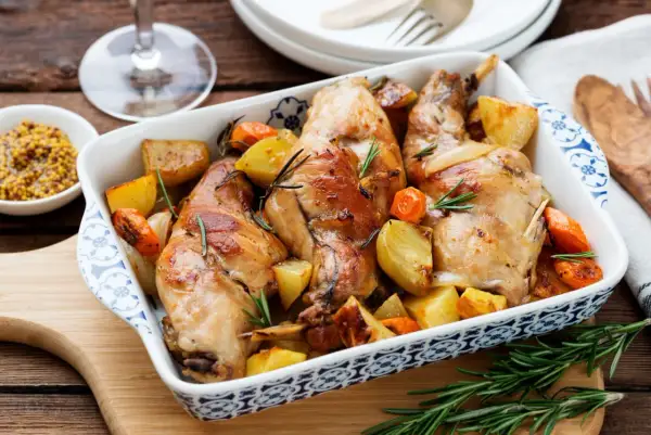 Delizioso coniglio al forno con patate e carote, profumato al rosmarino. Un piatto rustico e saporito, pronto per essere gustato.