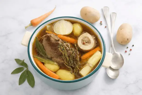 Un ricco brodo di carne con ossobuco, patate, carote, cipolla e erbe aromatiche. Un piatto confortante e saporito.