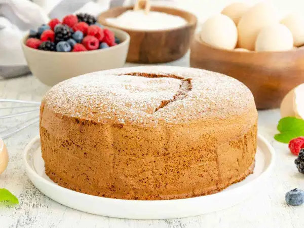 Una soffice torta margherita spolverata di zucchero a velo, pronta per essere gustata con frutti di bosco freschi.