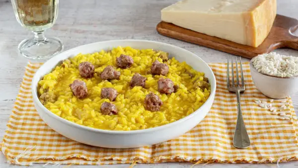 Un invitante risotto alla monzese, giallo intenso e arricchito da pezzetti di salsiccia, pronto per essere gustato.