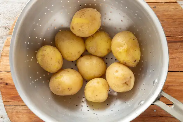 Patate bollite appena scolate in un colino, pronte per essere condite.