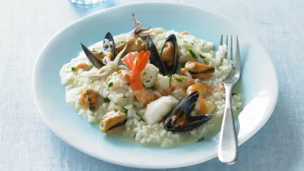Un cremoso risotto alla pescatora, ricco di gamberi, cozze e calamari, pronto per essere gustato.