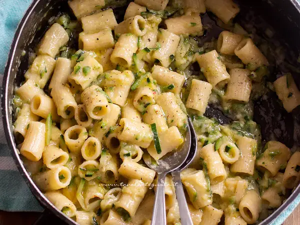 Close-up of rigatoni pasta with zucchini in a creamy sauce in a pot.