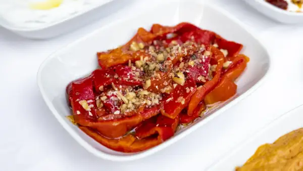 Peperoni al microonde, dolci e succosi, conditi con aglio tritato e spezie, serviti in una ciotola bianca.